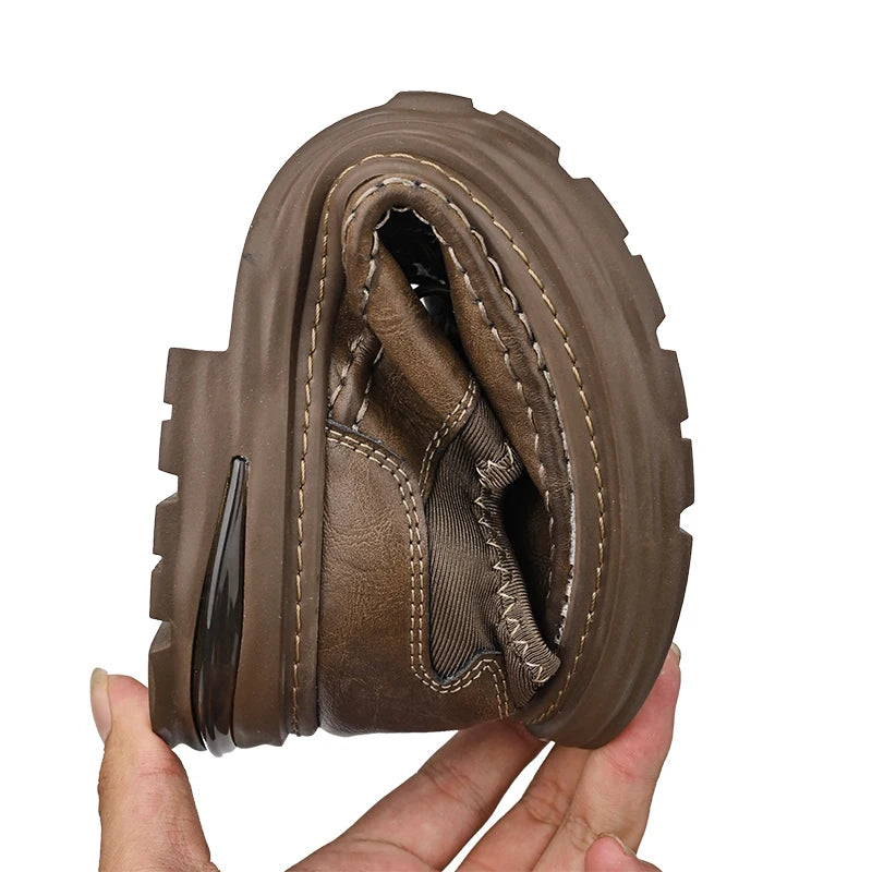 Brown leather boot sole held by a hand on a white background