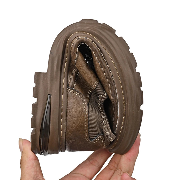 Brown leather boot sole held by a hand on a white background