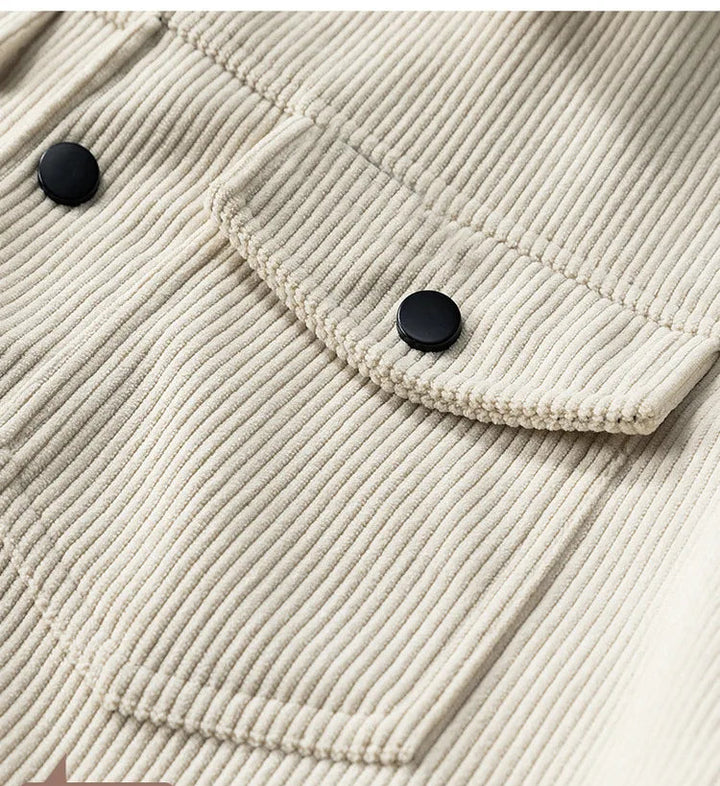 Close-up of a beige corduroy jacket with black buttons and a pocket detail.