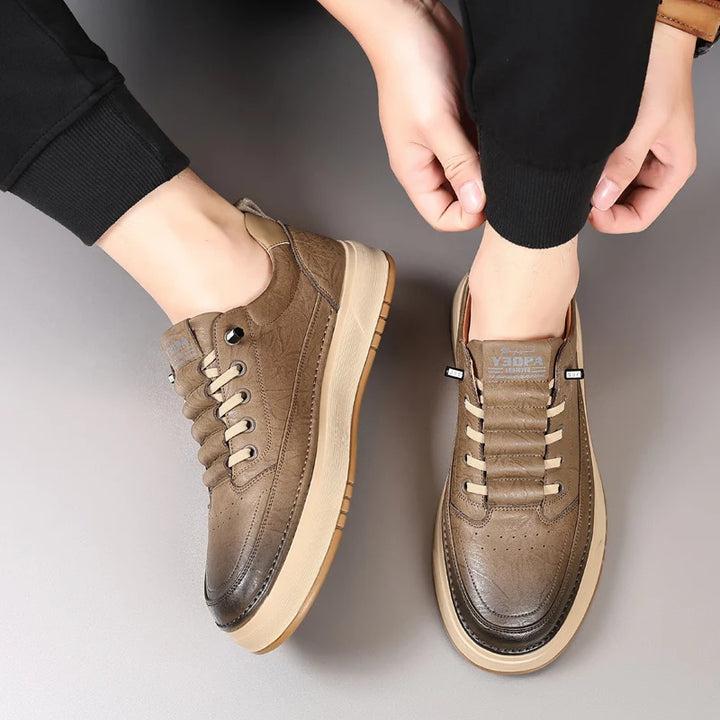 Brown sneakers worn by a person on a gray background
