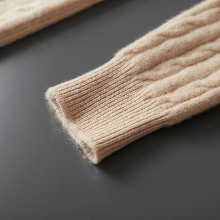 Close-up of beige knitted sweater sleeve on a dark surface