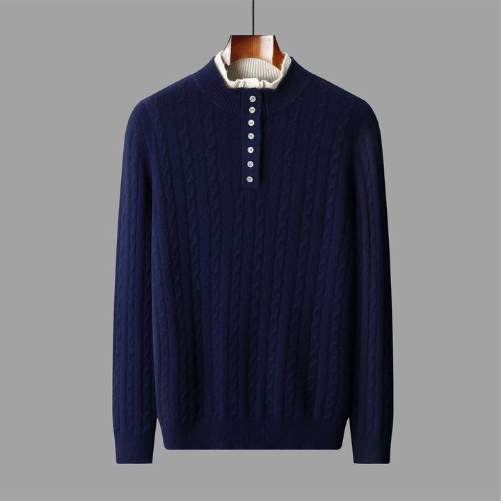 Navy blue cable knit sweater on a hanger against a gray background