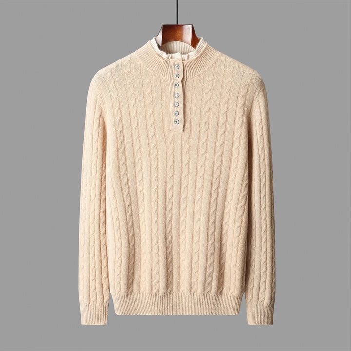 Beige cable knit sweater on a hanger against a gray background