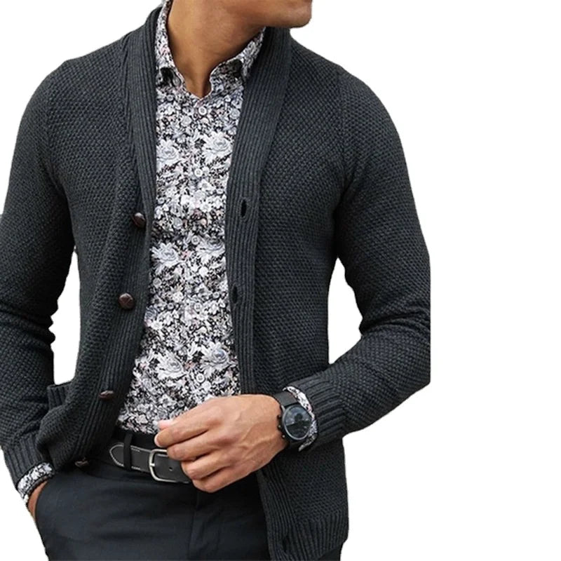 Man wearing a dark gray cardigan over a patterned shirt on a white background