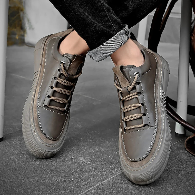 Gray sneakers worn by a person on a gray floor.