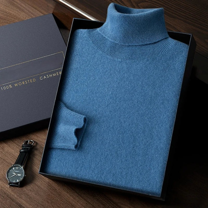 Folded blue turtleneck sweater in a box with a black watch on a wooden surface