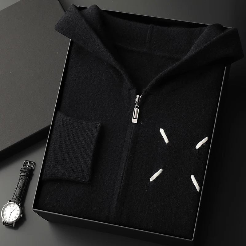 Black hoodie with white star designs in a box, next to a black watch on a dark surface.
