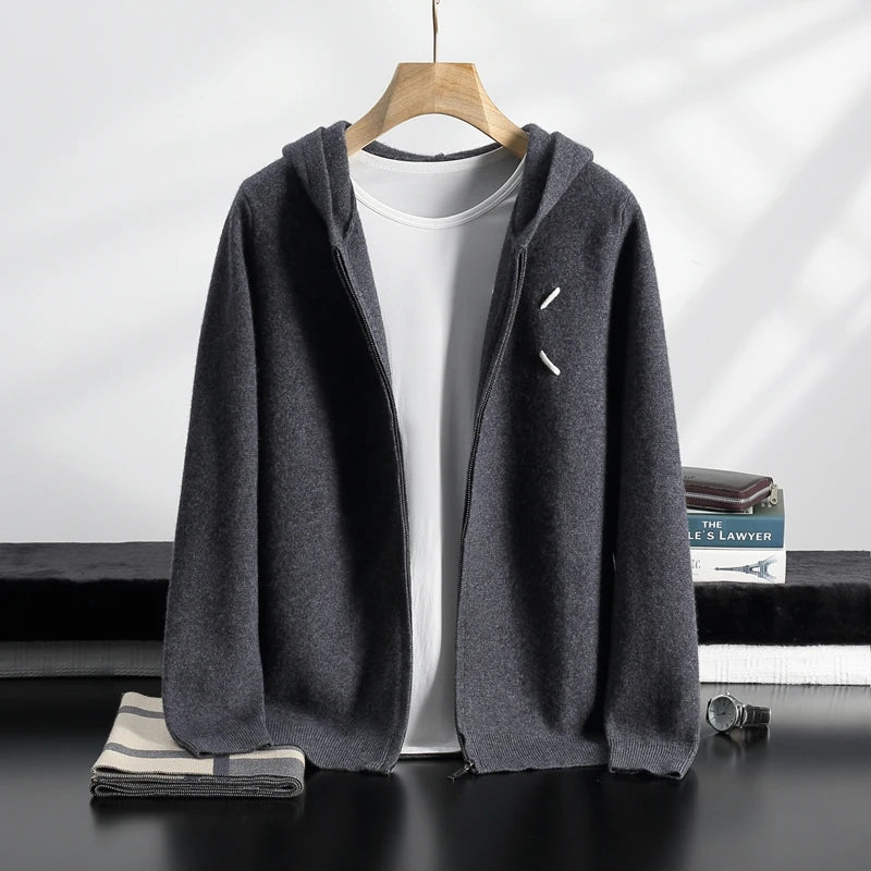 Gray hoodie on a hanger with a white shirt underneath, on a dark surface with books in the background.