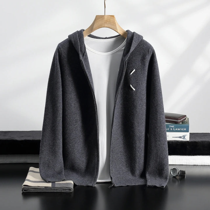 Gray hoodie on a hanger with a white shirt underneath, on a dark surface with books in the background.