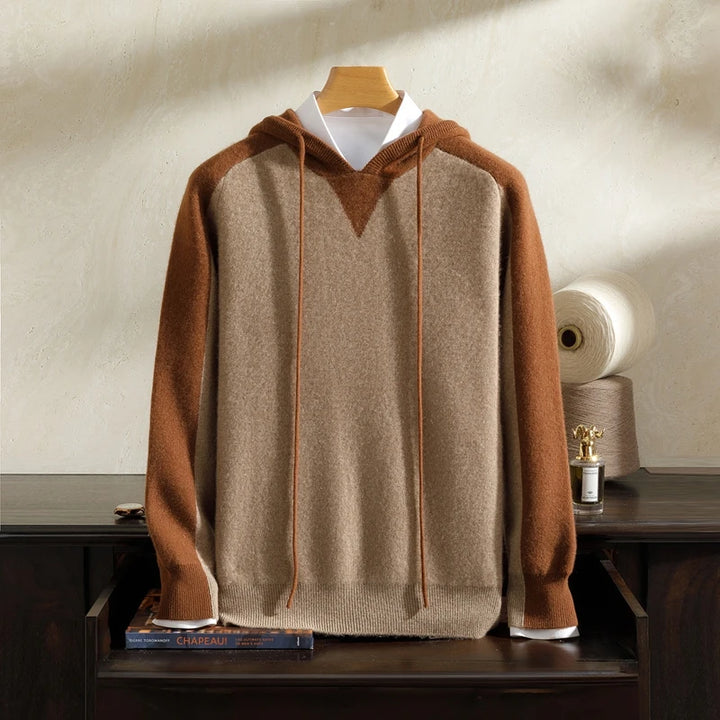 Brown and beige hoodie on a wooden hanger against a neutral background