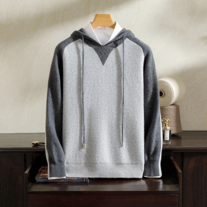 Gray hoodie on a wooden hanger against a neutral background