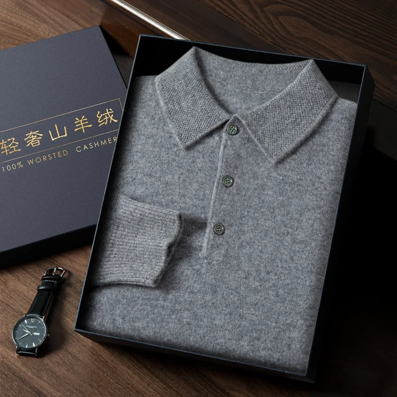 Folded gray cashmere polo shirt in a box with a watch on a wooden surface