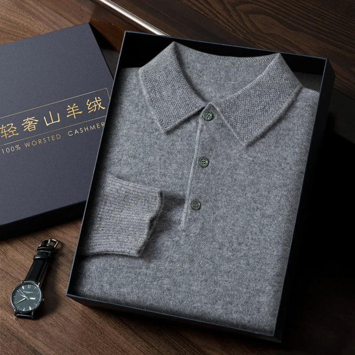 Folded gray cashmere polo shirt in a box with a watch on a wooden surface
