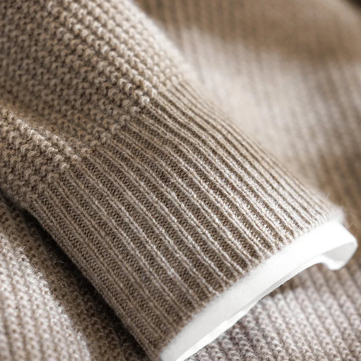 Close-up of a beige knitted sweater with a white lining.