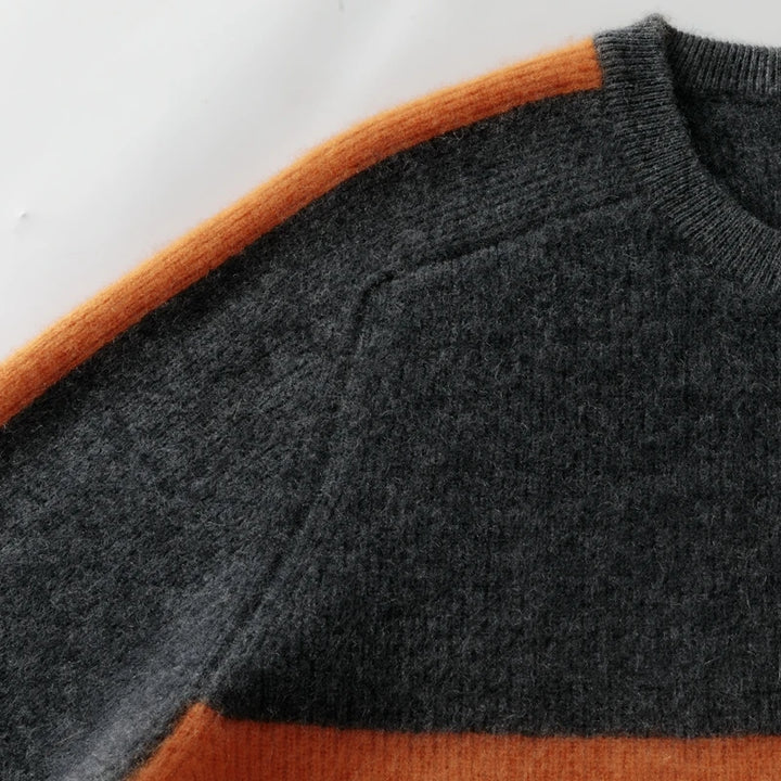 Close-up of a gray sweater with orange accents on a white background