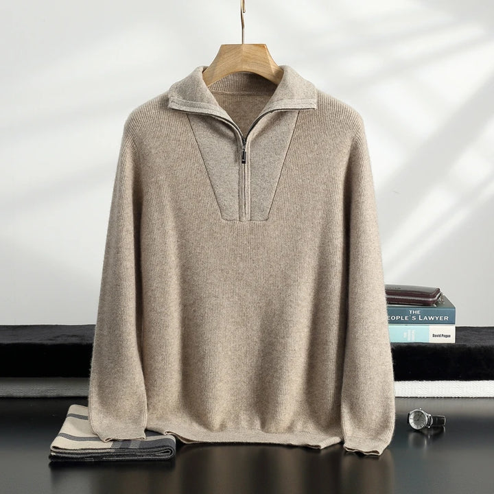 Beige half-zip sweater on a hanger with books and a watch in the background