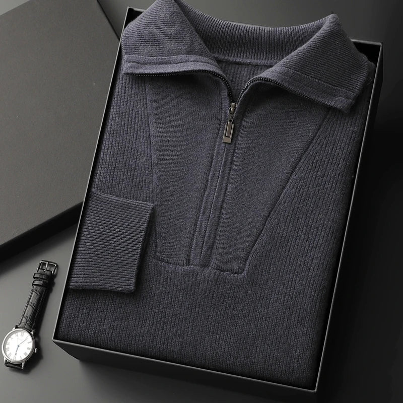 Dark gray zip-up sweater in a box with a watch on a dark surface