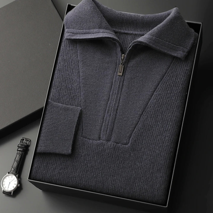 Dark gray zip-up sweater in a box with a watch on a dark surface
