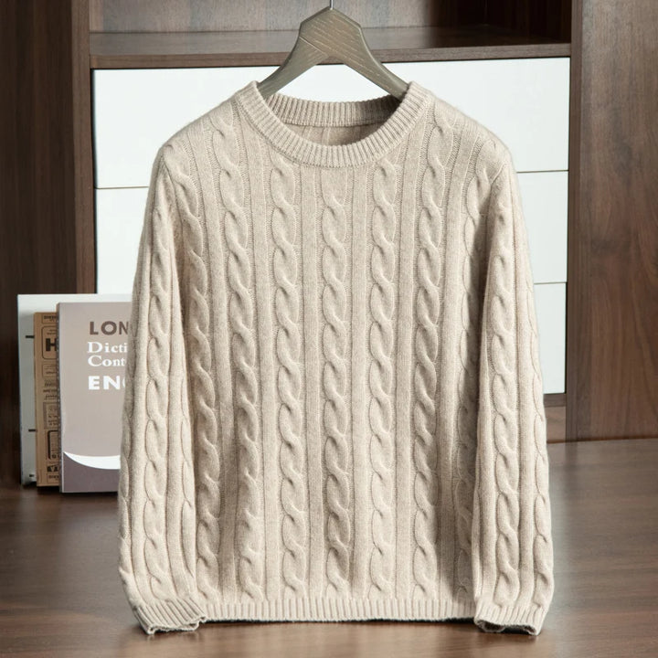 Beige cable knit sweater on a hanger against a neutral background
