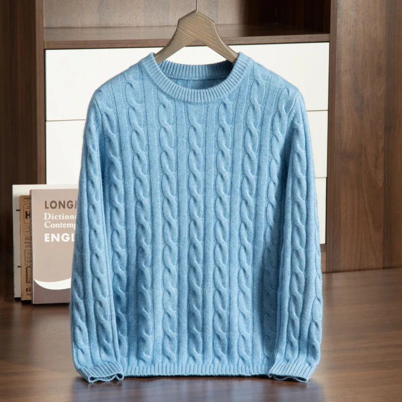 Blue cable knit sweater on a hanger against a wooden background