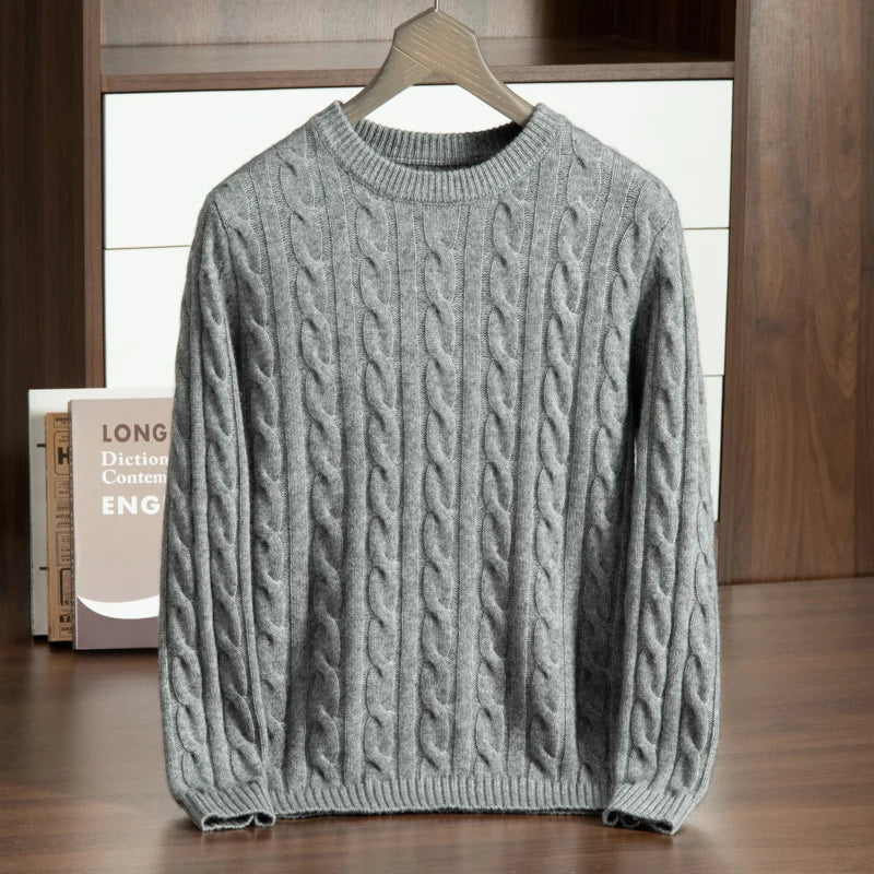Gray cable knit sweater on a hanger against a wooden background