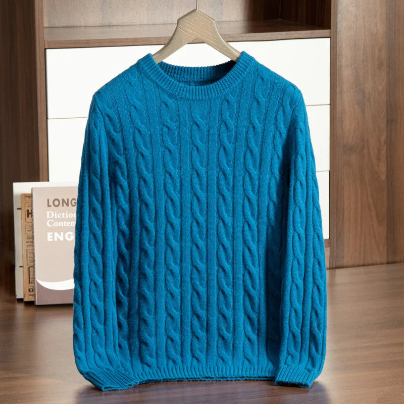 Blue cable knit sweater on a wooden hanger against a neutral background