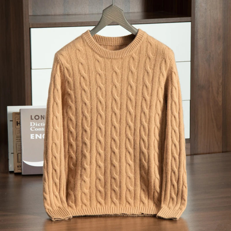 Beige cable knit sweater on a hanger against a wooden background