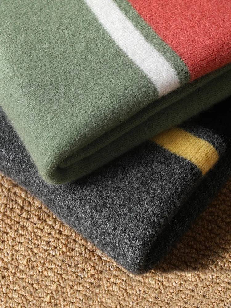 Folded fleece blankets in green, red, gray, and yellow on a textured surface