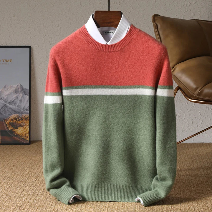 Color-blocked sweater with red, gray, and green sections on a hanger against a neutral background.