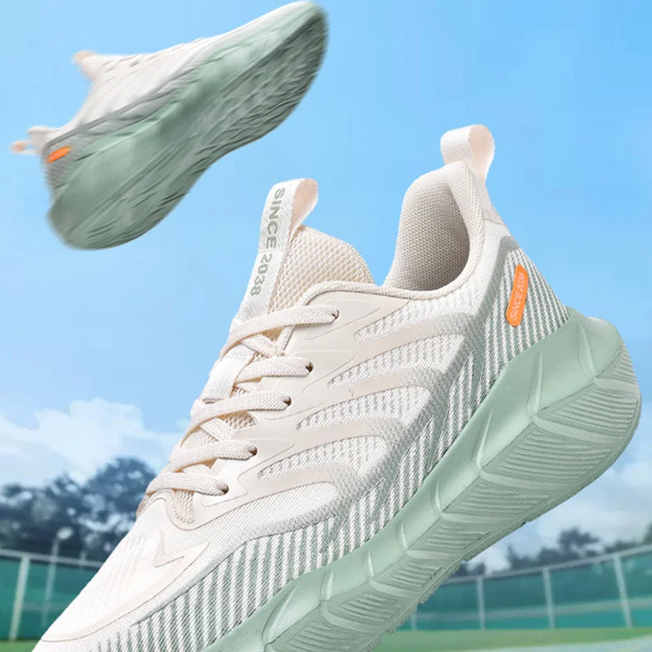 White and light green running shoes with orange accents on a blurred outdoor background
