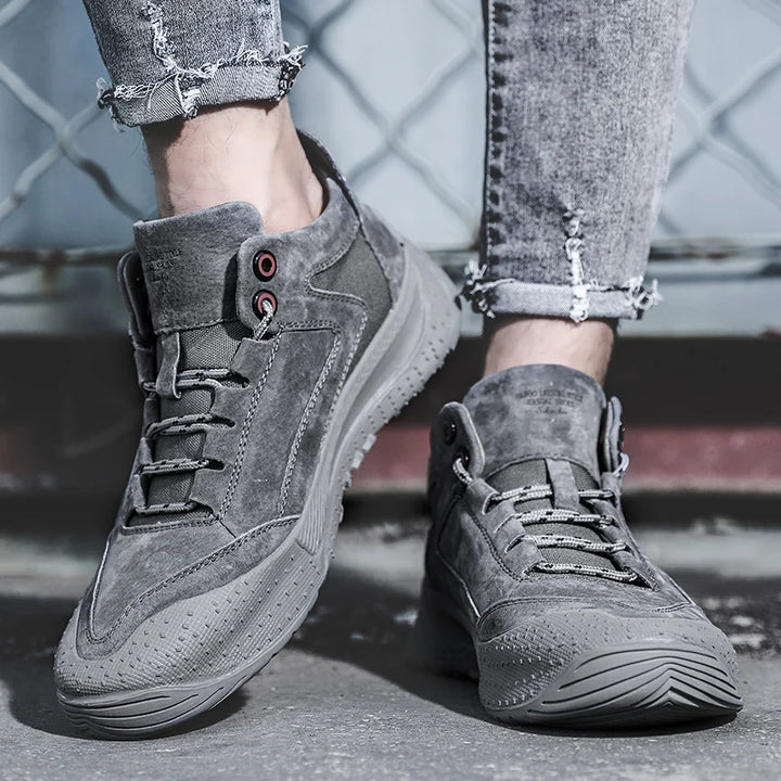 Gray suede high-top sneakers worn with ripped jeans against a blurred background