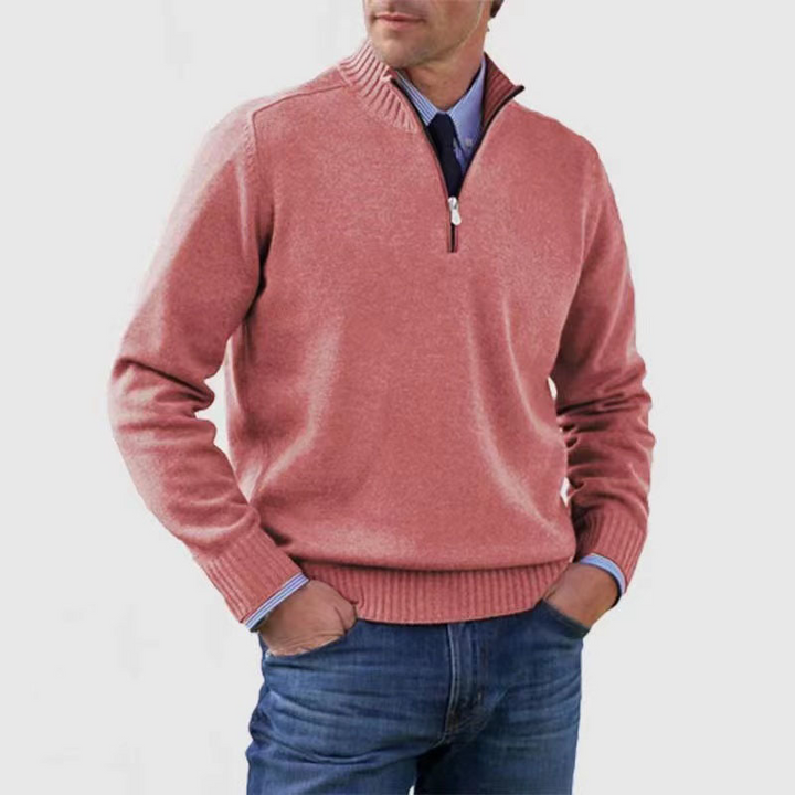 Man wearing a pink half-zip sweater and blue jeans on a white background