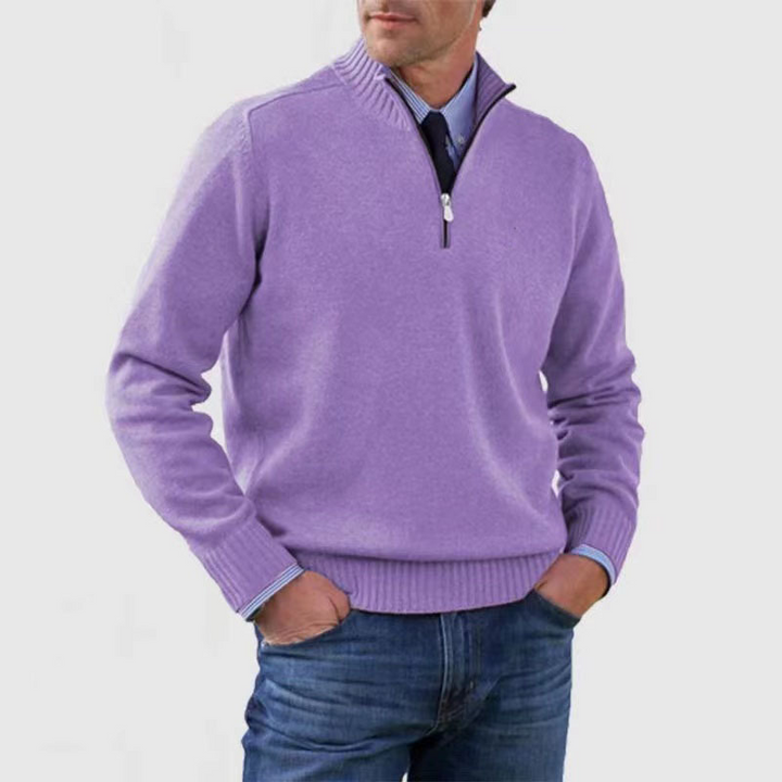 Man wearing a purple quarter-zip sweater and blue jeans on a white background