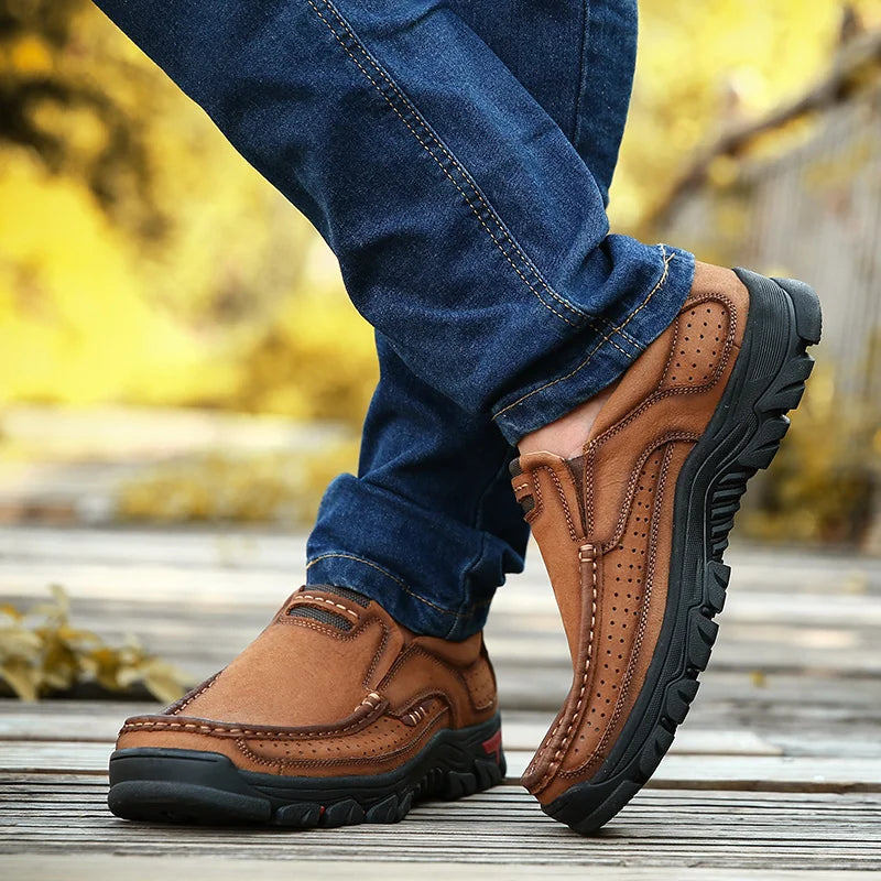 Brown shoes worn with blue jeans on a blurred natural background
