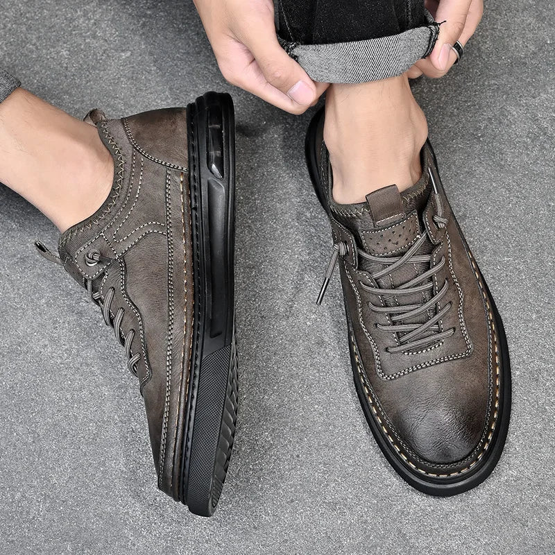 Brown leather shoes worn by a person on a gray floor.