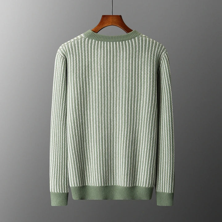 Green and white striped sweater on a hanger against a gray background