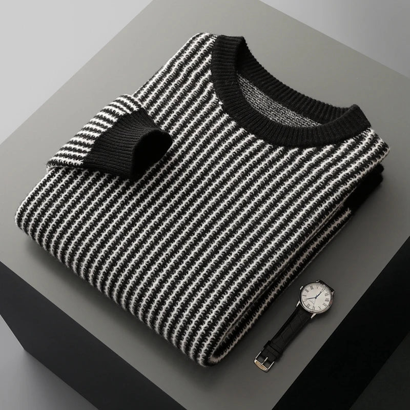 Folded black and white striped sweater with a watch on a gray surface