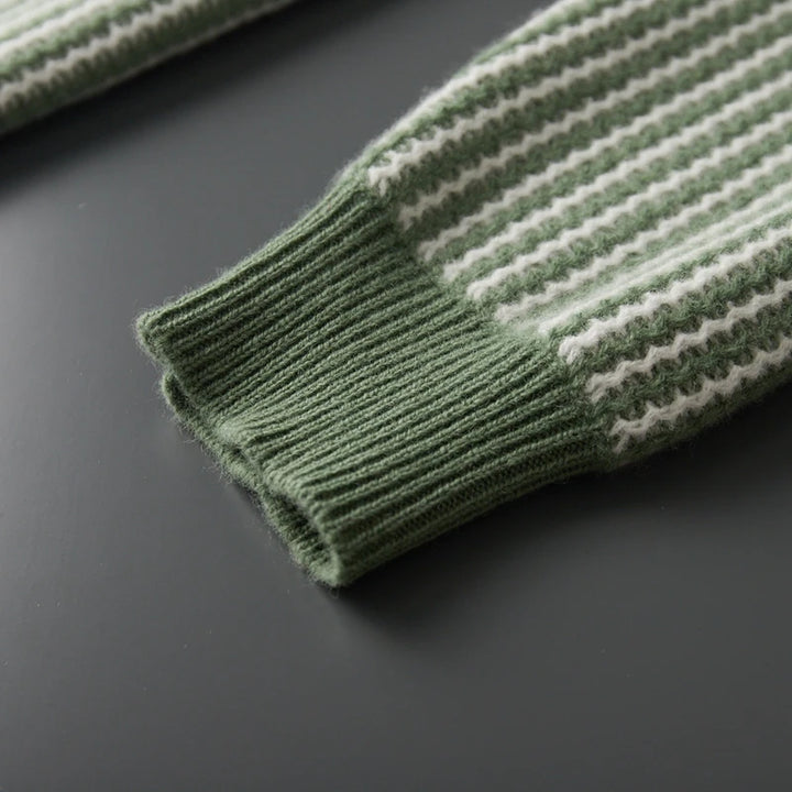 Close-up of a green and white striped sweater sleeve on a dark surface