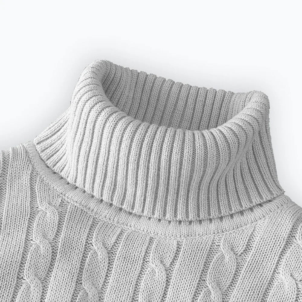 Close-up of a gray cable knit sweater with a white background