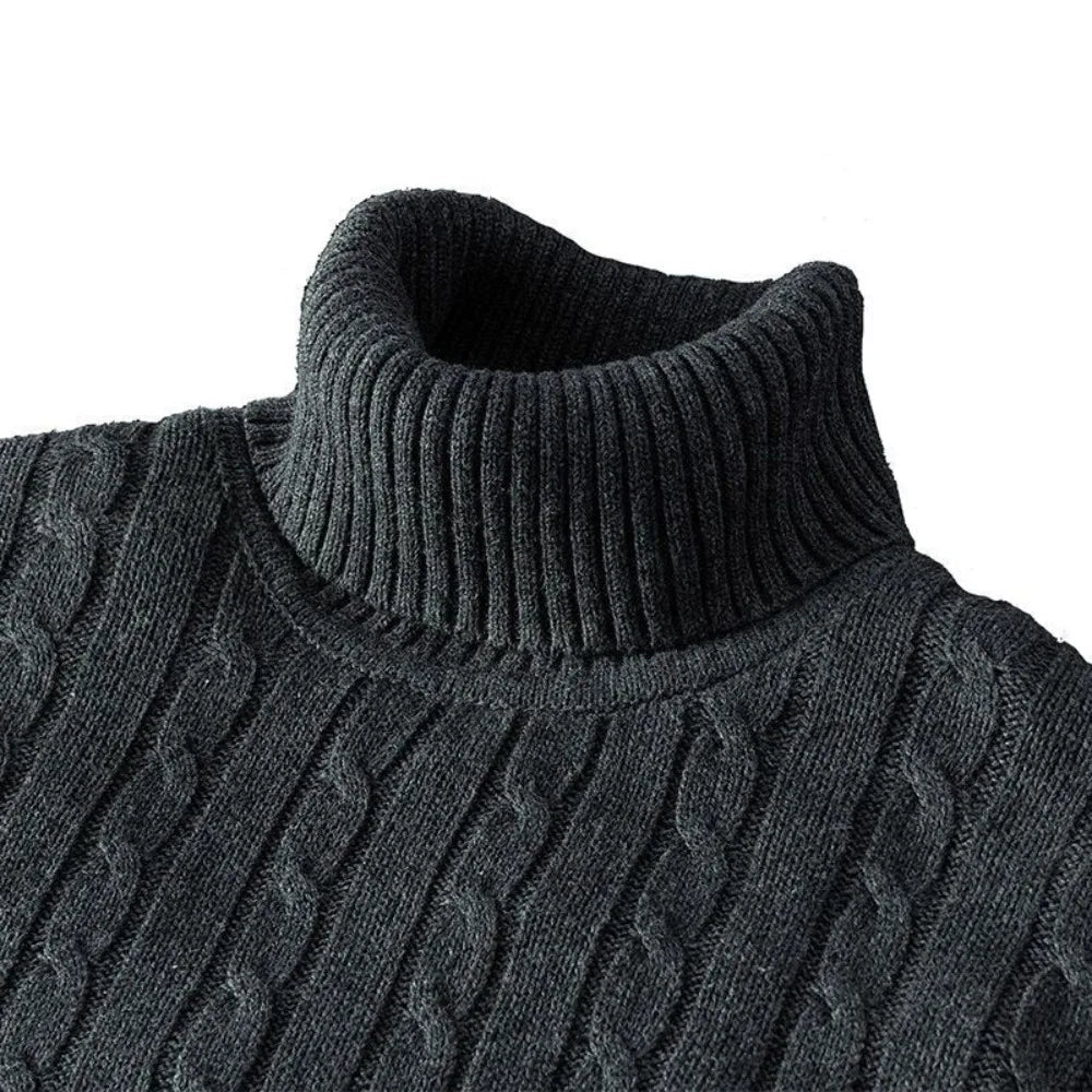 Close-up of a dark gray cable knit sweater with a high collar on a white background