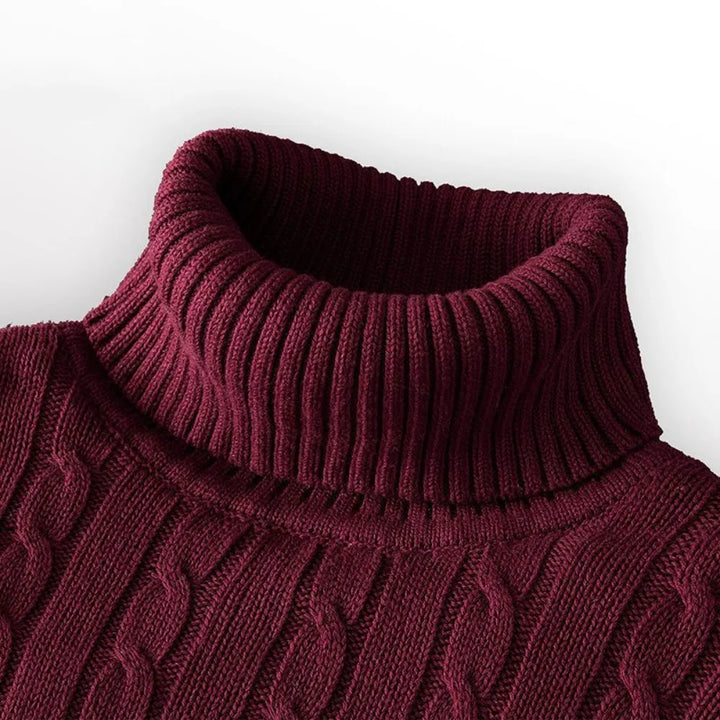 Close-up of a maroon cable knit sweater on a white background