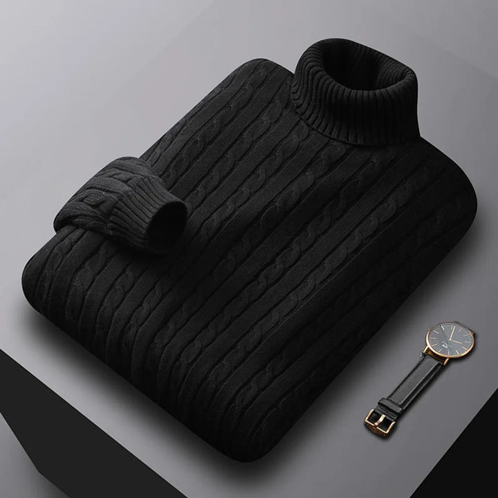 Black ribbed sweater on a gray surface with a watch beside it