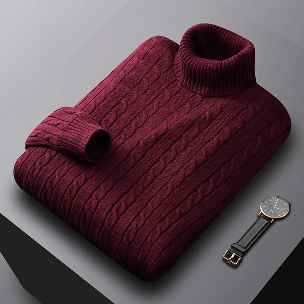 Folded burgundy sweater with a watch on a gray surface