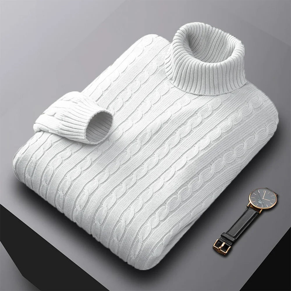 White cable knit sweater on a gray background with a watch.