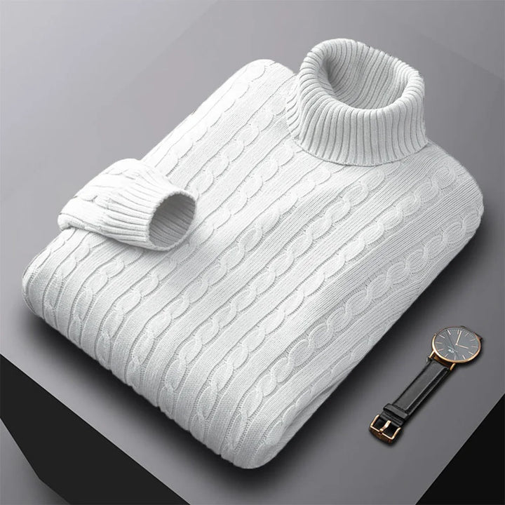 White cable knit sweater on a gray background with a watch.