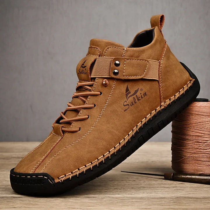 Brown leather shoe with black sole on a wooden surface, featuring the brand 'Salkin'.