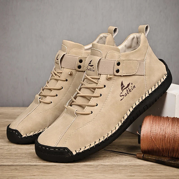 Beige sneakers with black soles on a wooden surface, featuring the Salkin brand.
