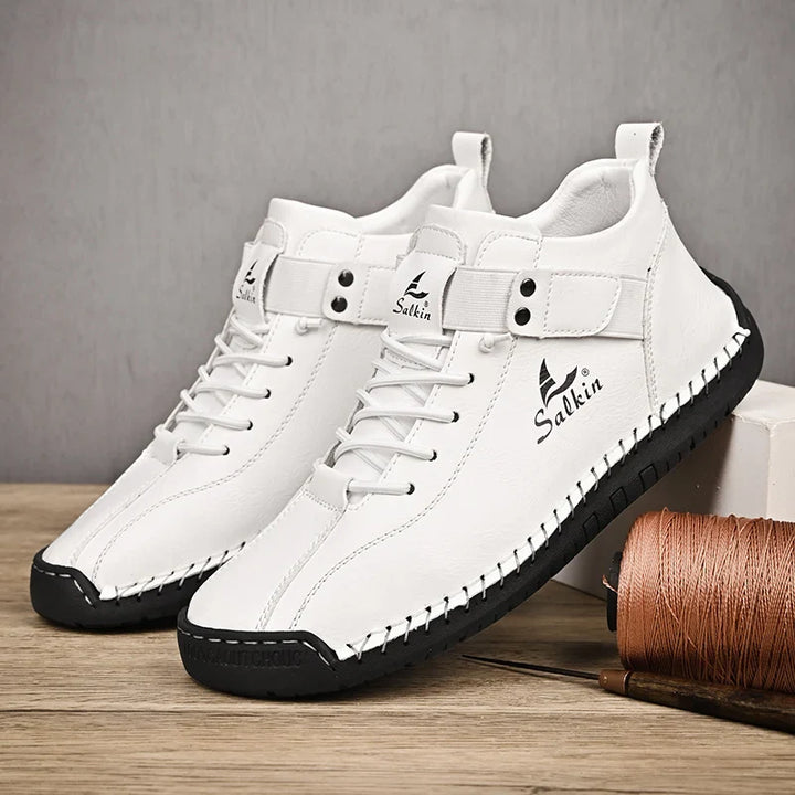 White sneakers with black soles on a wooden surface with a gray background