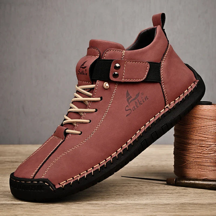 Brown leather shoe with black sole on a wooden surface, featuring the brand 'Sukhin'.
