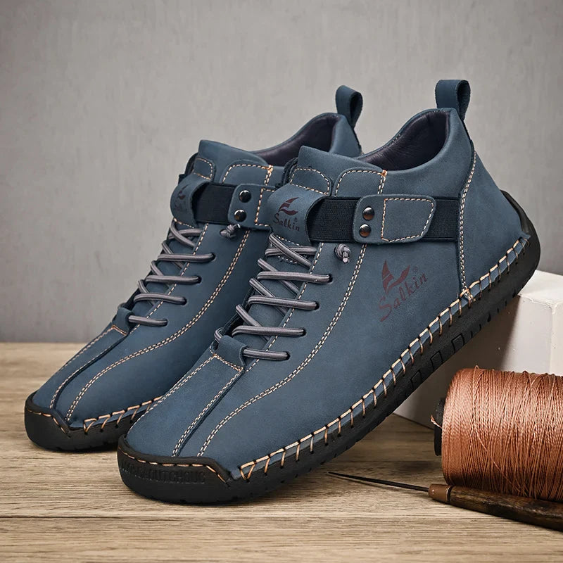 Blue leather shoes with black soles on a wooden surface with a gray background